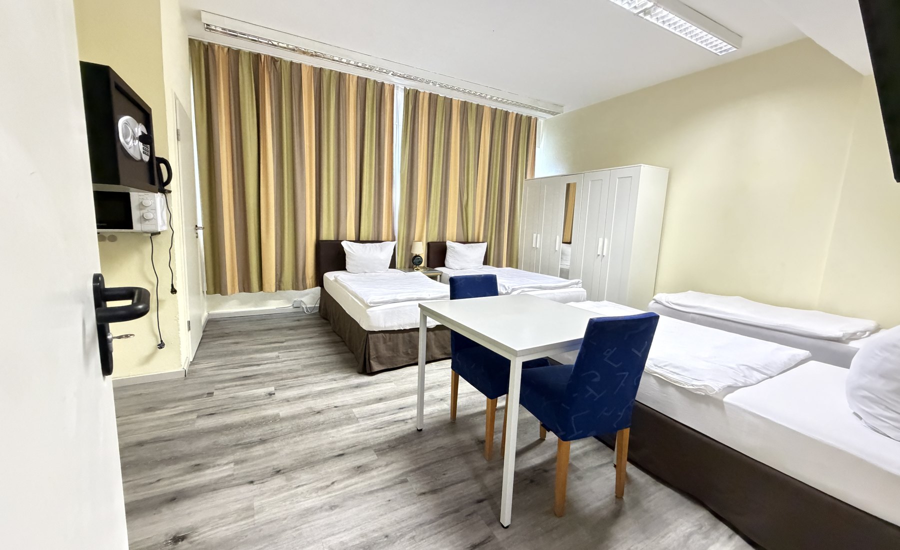 Helles LIMOSTAY Mehrbettzimmer mit Tisch und Schrank